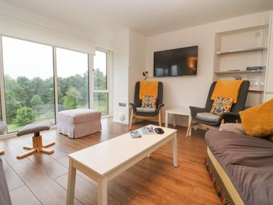 A living room with chairs a sofa a coffee table and large windows showing trees at Beautiful Cotswold View in Bourton-On-The-Water