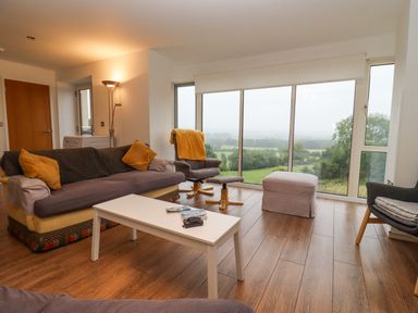 A living room with sofas chairs and a white coffee table overlooking the countryside at Beautiful Cotswold View in Bourton-On-The-Water