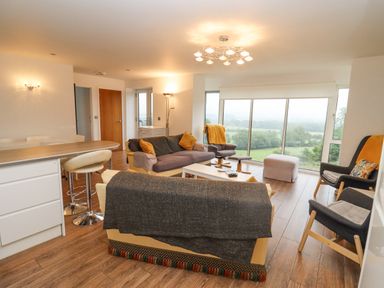 A living room with sofas armchairs and large windows overlooking greenery at Beautiful Cotswold View in Bourton-On-The-Water