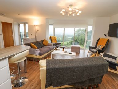 A living room with sofas chairs and a coffee table in front of large windows overlooking a green landscape at Beautiful Cotswold View in Bourton-On-The-Water