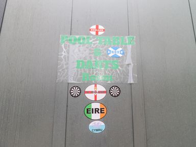 A sign with green text saying pool table and darts room and flags of England Scotland Northern Ireland Eire and Cymru on a gray wooden wall at Beautiful Cotswold View in Bourton-On-The-Water