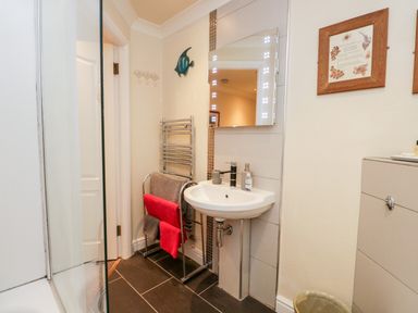 A bathroom with a sink mirror towel rack and framed pictures at Church View in Ambleside