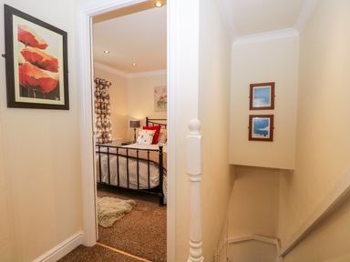 A hallway showing a stairway and a bedroom with a black metal bed frame at Church View in Ambleside