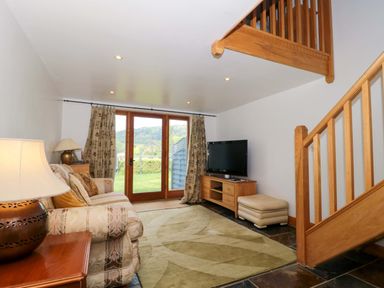 A living room with a sofa and television at Longside in Gilwern