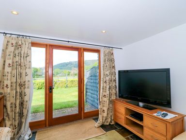 A living room with a TV and windows at Longside in Gilwern