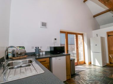 A kitchen with a sink, refrigerator, and appliances at Longside in Gilwern
