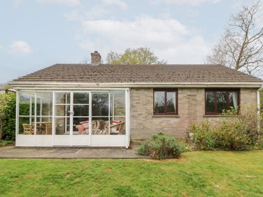 A single story brick house with a glass enclosed porch and lawn at Bryn yr Haf in Llanfair Clydogau near Lampeter
