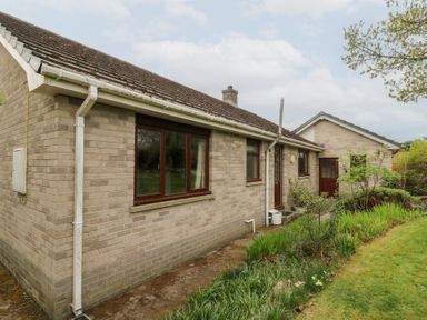 A brick house with windows and doors surrounded by a garden and grass at Bryn yr Haf in Llanfair Clydogau near Lampeter