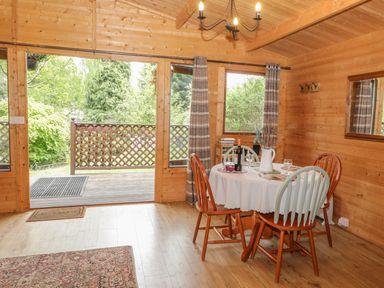 A dining area with a round table and four chairs inside a wooden cabin at Y Caban in Llechwedd The Conwy Valley