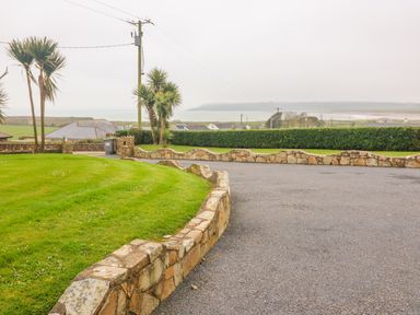 A paved driveway with stone walls and green grass with palm trees and a view of the sea at Island View in Ardmore County Waterford