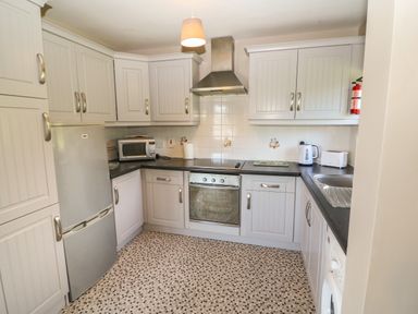 A kitchen with white cabinets a stainless steel refrigerator oven microwave kettle toaster and a washing machine at Island View in Ardmore County Waterford
