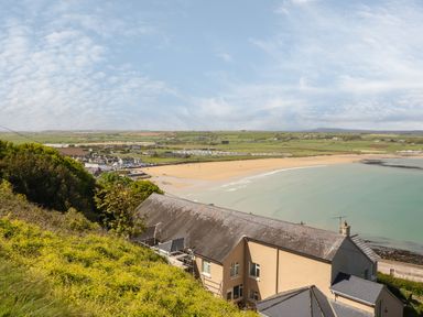 A coastal view of a sandy beach with houses and green fields in the background at Island View in Ardmore County Waterford