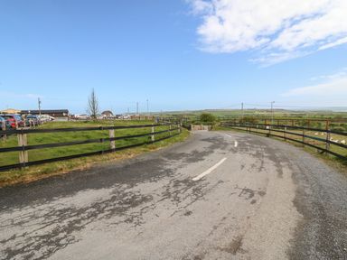 A country road lined with wooden fences with parked cars and fields under a blue sky at Island View in Ardmore County Waterford