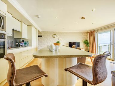 A kitchen with a large island and bar stools with leather seats at Solway Cottage in Bowness-on-Solway near Wigton
