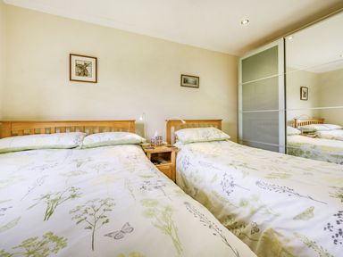 A bedroom with two beds and a nightstand between them at Solway Cottage in Bowness-on-Solway near Wigton