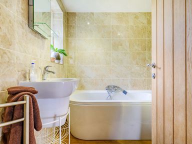 A bathroom with a bathtub sink tiled walls and a wooden door at Solway Cottage in Bowness-on-Solway near Wigton
