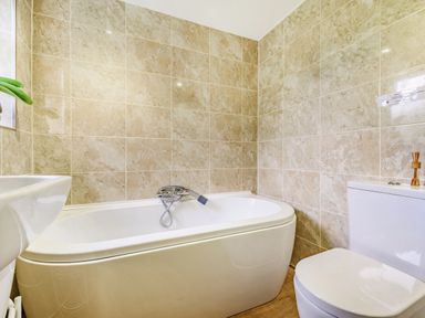 A bathroom with a bathtub a toilet and a sink with tiled walls at Solway Cottage in Bowness-on-Solway near Wigton