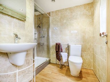 A bathroom with a sink a shower with glass door a toilet and towel rack with towels at Solway Cottage in Bowness-on-Solway near Wigton
