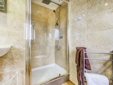 A bathroom with a glass enclosed shower and a towel rack with towels at Solway Cottage in Bowness-on-Solway near Wigton