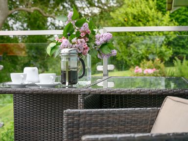 An outdoor table with a coffee press cups and a vase of flowers at Solway Cottage in Bowness-on-Solway near Wigton