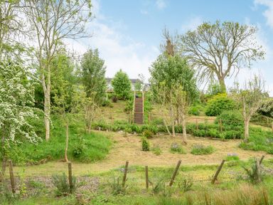 A garden with a grassy slope trees and wooden stairs at Solway Cottage in Bowness-on-Solway near Wigton