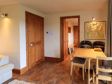 A dining area with a wooden table and chairs near two wooden doors at Walkers Retreat in Ambleside