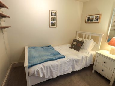 A small bedroom with a single bed white bedside table and lamp at Walkers Retreat in Ambleside