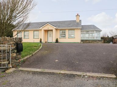 A one-story house with a driveway and a lawn surrounded by a stone wall at Raheen in Castletownshend County Cork