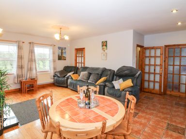 A living room with green sofas and a round wooden dining table at Raheen in Castletownshend County Cork
