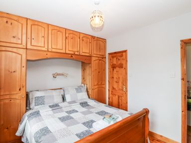 A bedroom with a wooden bed and built-in wooden wardrobes at Raheen in Castletownshend County Cork