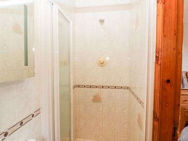 A shower area with tiled walls and a glass door at Raheen in Castletownshend County Cork