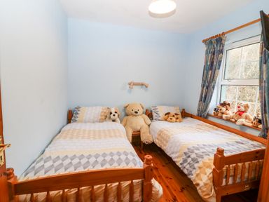 A bedroom with two single beds and stuffed animals on the beds and windowsill at Raheen in Castletownshend County Cork