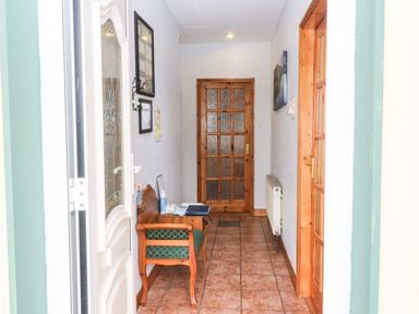 A hallway with a wooden bench and a wooden door at the end at Raheen in Castletownshend County Cork