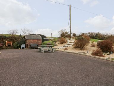 An outdoor area with a gravel path, a small wooden shed, benches, a rotary clothesline, and bushes at Raheen in Castletownshend County Cork