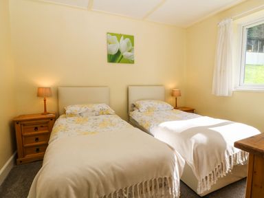 A bedroom with two single beds with floral bedding and bedside tables with lamps at Bron Aber Arthog near Dolgellau