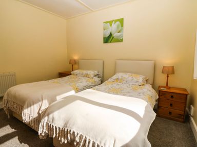 A bedroom with two single beds bedside tables and lamps at Bron Aber Arthog near Dolgellau 
