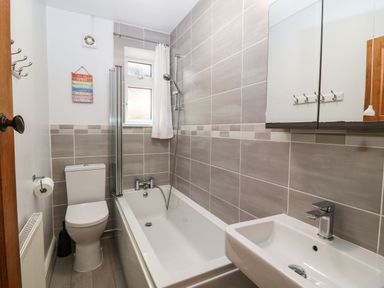 A bathroom with a bathtub shower toilet and sink at Bron Aber in Arthog near Dolgellau