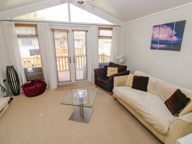 A living room with a sofa armchair glass coffee table and wall art at Cladebrine Wisemans Bridge near Saundersfoot