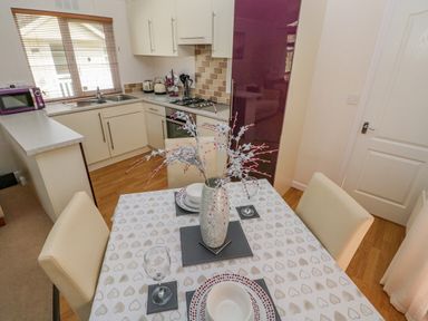 A dining table with plates bowls glasses and a vase with decorative branches in a kitchen at Cladebrine Wisemans Bridge near Saundersfoot