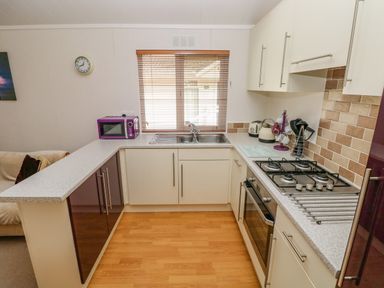 A kitchen with a gas stove sink microwave and utensils at Cladebrine Wisemans Bridge near Saundersfoot