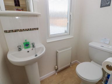 A bathroom with a sink a toilet a window a radiator and a mirror at Cladebrine Wisemans Bridge near Saundersfoot