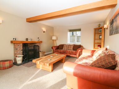 A living room with two sofas a wooden coffee table and a brick fireplace at Ty Top in Llanfaethlu