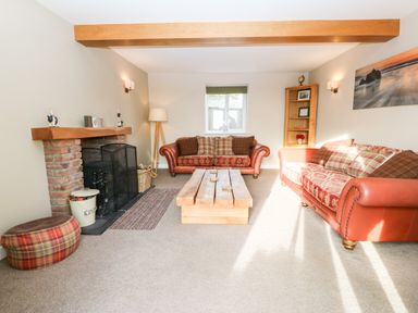 A living room with two sofas a wooden coffee table and a brick fireplace at Ty Top in Llanfaethlu