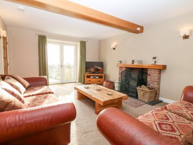 A living room with sofas a wooden coffee table a fireplace and a television at Ty Top in Llanfaethlu