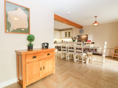 A dining room with a wooden sideboard and a dining table with chairs at Ty Top in Llanfaethlu