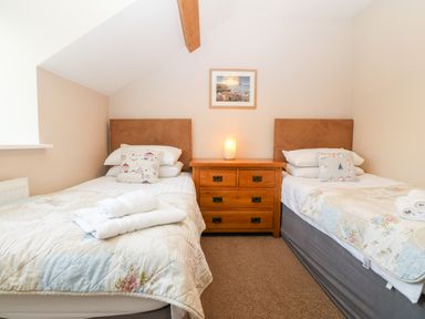 A bedroom with two single beds and a wooden bedside table with a lamp at Ty Top in Llanfaethlu