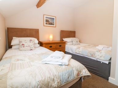 A bedroom with two single beds a wooden nightstand and a framed picture on the wall at Ty Top in Llanfaethlu