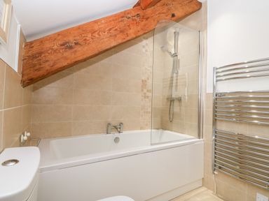 A bathroom with a bathtub shower and towel rack at Ty Top in Llanfaethlu