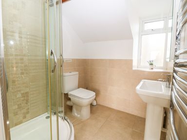 A bathroom with a shower cubicle toilet sink and window at Ty Top in Llanfaethlu