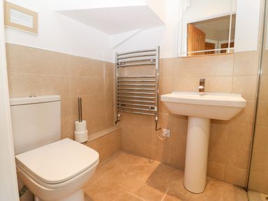 A bathroom with a toilet a pedestal sink a towel warmer and a toilet paper holder at Ty Top in Llanfaethlu